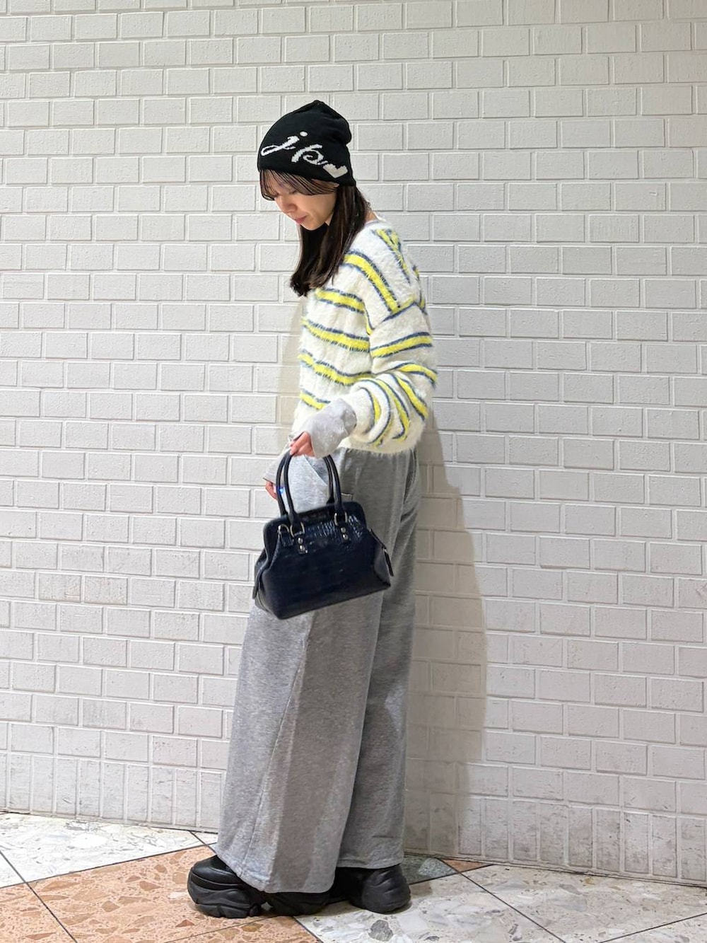 ブラック系のブーツ、ブルー系のハンドバッグ、ホワイト系のニット/セーターを着用したレディースの冬コーディネートの3枚目の写真