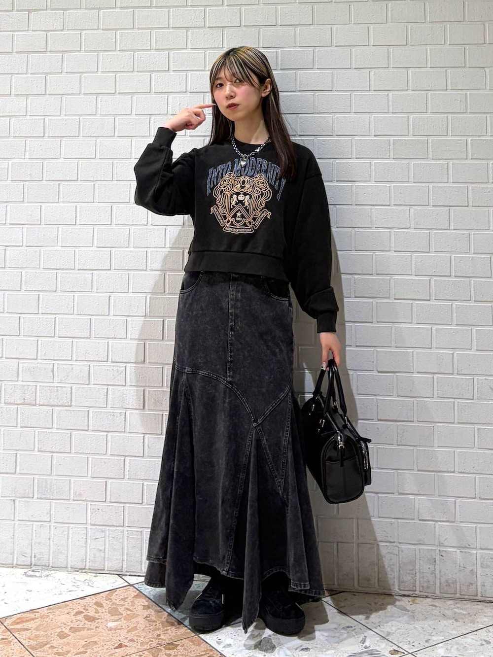 グレー系のスウェット、ブラック系のショルダーバッグ、ブラック系のデニムスカートを着用したレディースの春コーディネートの4枚目の写真