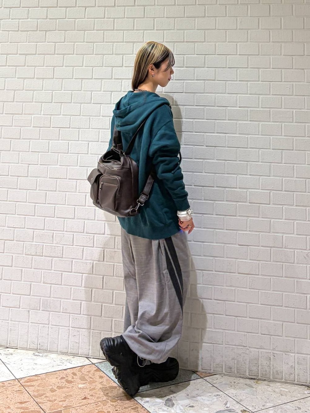 ブラック系のブーツ、グリーン系のパーカー、ブラウン系のショルダーバッグを着用したレディースの冬コーディネートの2枚目の写真