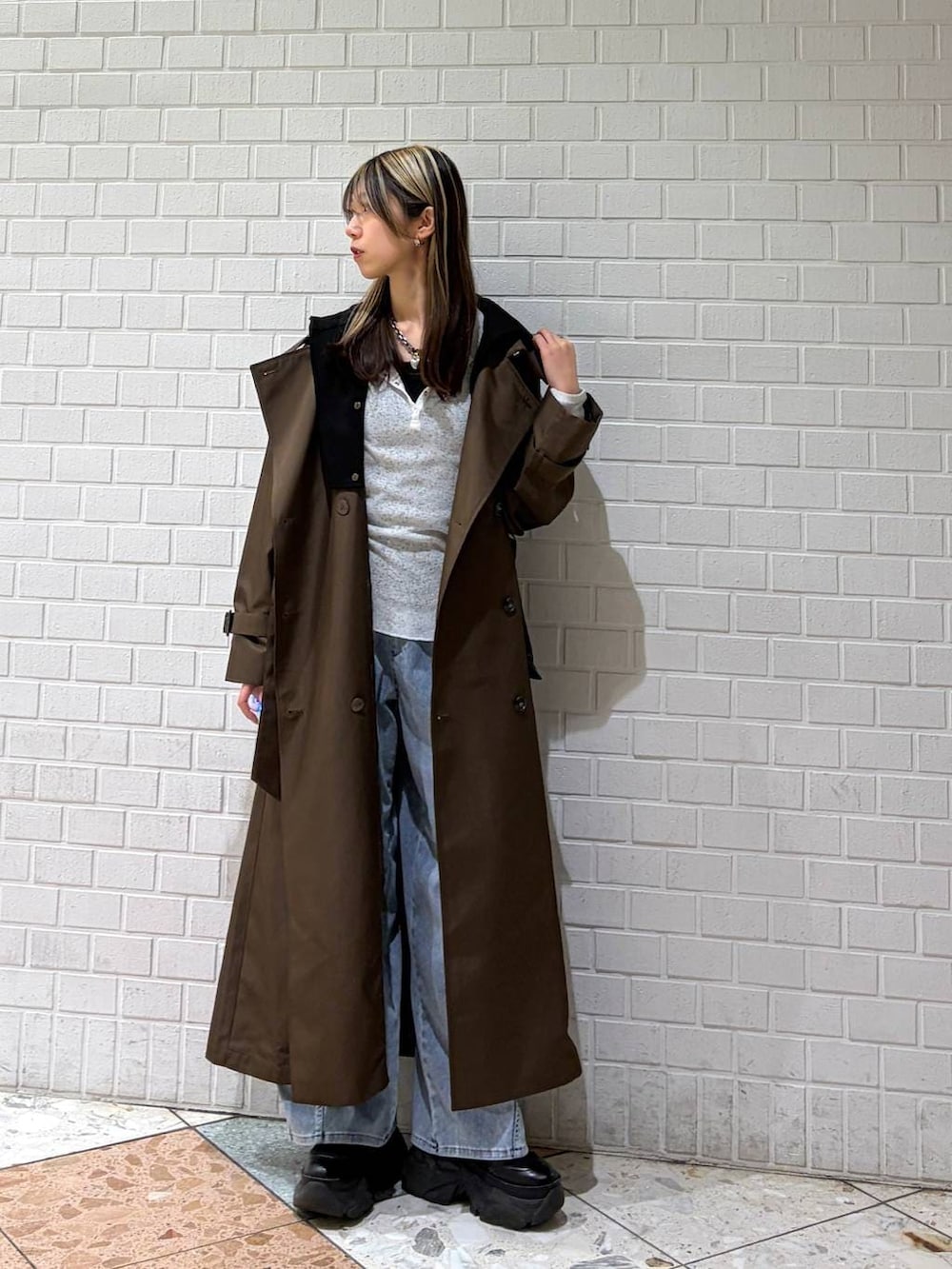 ブラック系のブーツ、ブラウン系のトレンチコート、ブルー系のデニムパンツを着用したレディースの春コーディネートの4枚目の写真