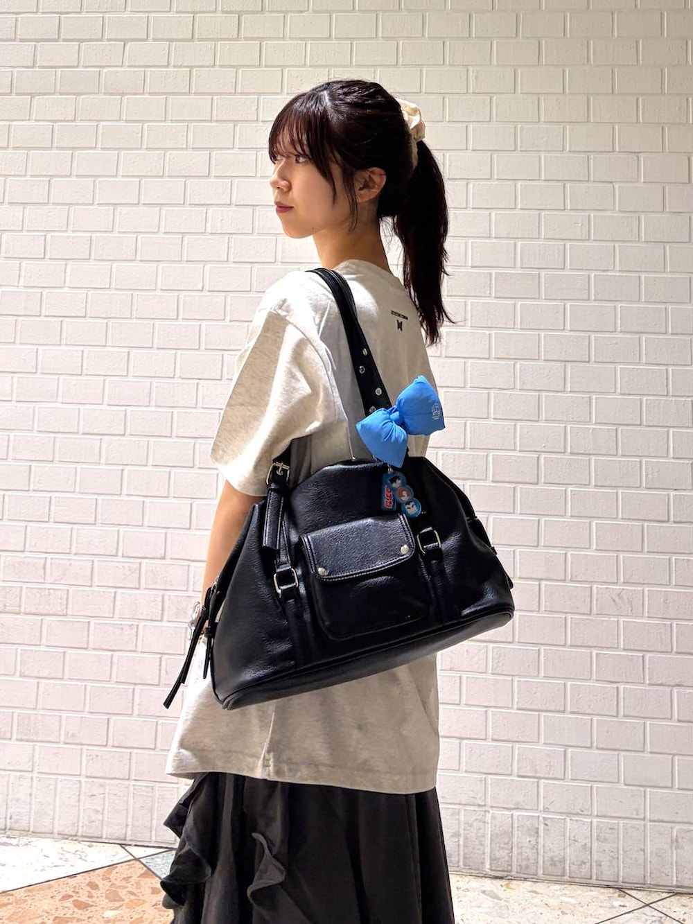 グレー系のスカート、ブラック系のボストンバッグ、ホワイト系のTシャツ/カットソーを着用したレディースの春コーディネートの6枚目の写真