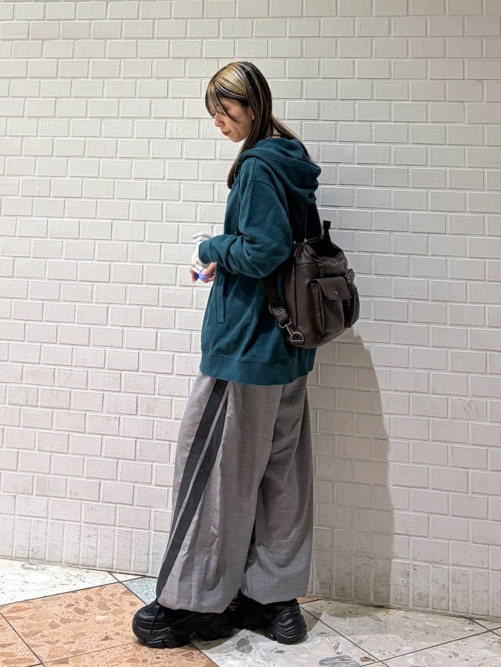 ブラック系のブーツ、グリーン系のパーカー、ブラウン系のショルダーバッグを着用したレディースの冬コーディネートの6枚目の写真