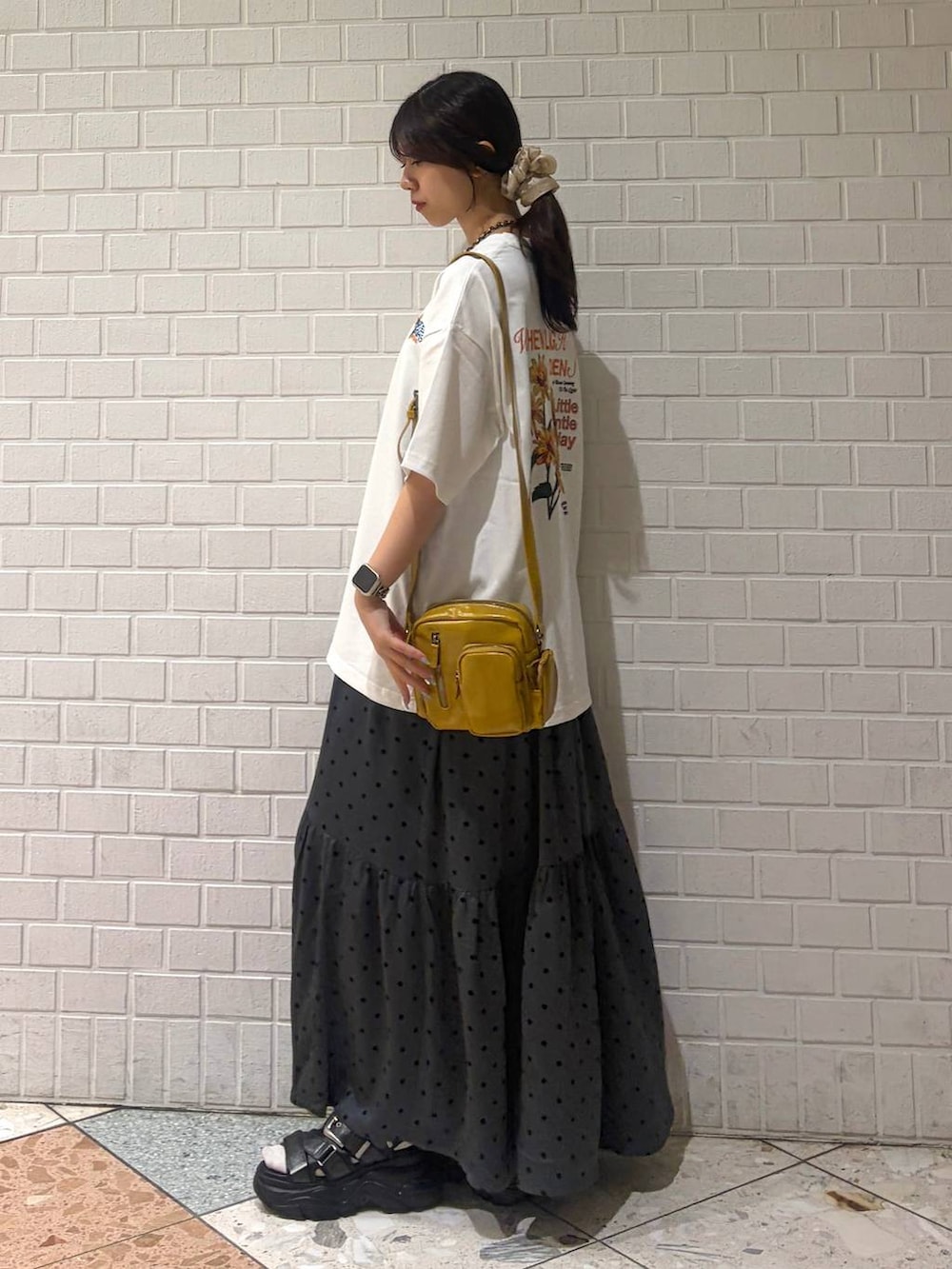イエロー系のショルダーバッグ、ブラック系のサンダル、ホワイト系のTシャツ/カットソーを着用したレディースの夏コーディネートの2枚目の写真