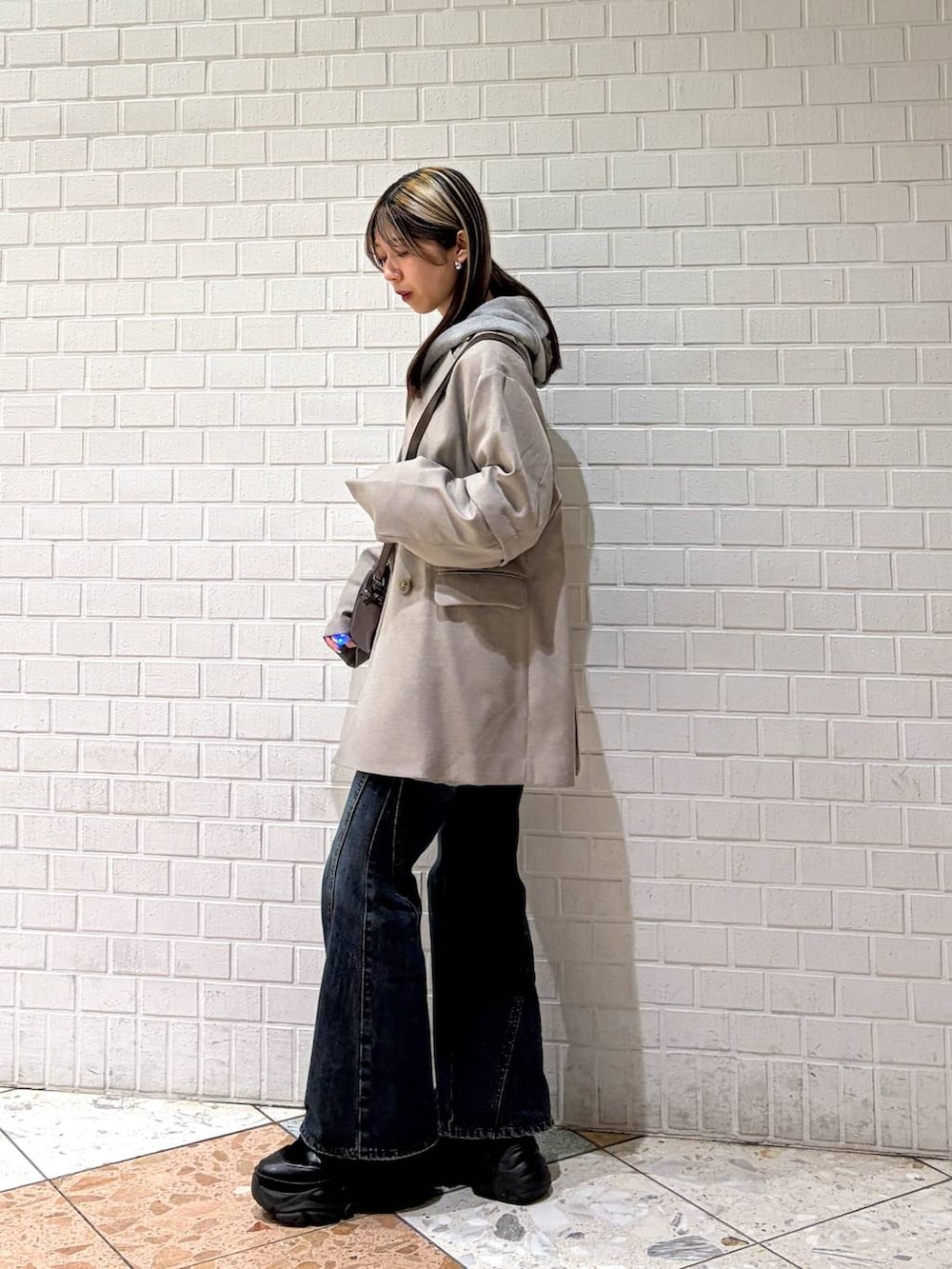 ブラック系のブーツ、ブルー系のデニムパンツ、グレー系のパーカーを着用したレディースの春コーディネートの3枚目の写真