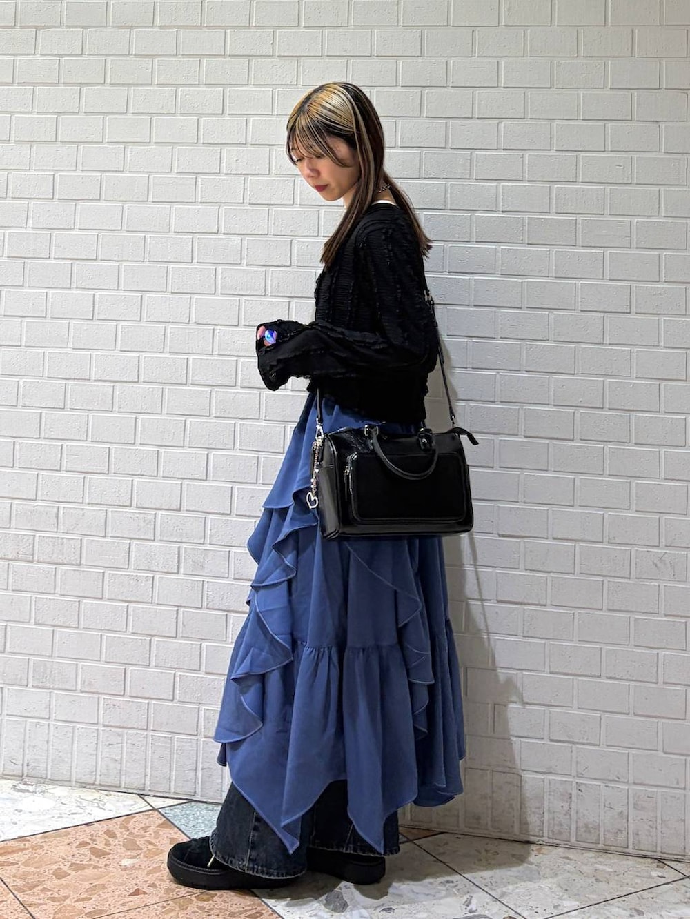 ブルー系のデニムパンツ、ブルー系のスカート、ブラック系のショルダーバッグを着用したレディースの春コーディネートの2枚目の写真