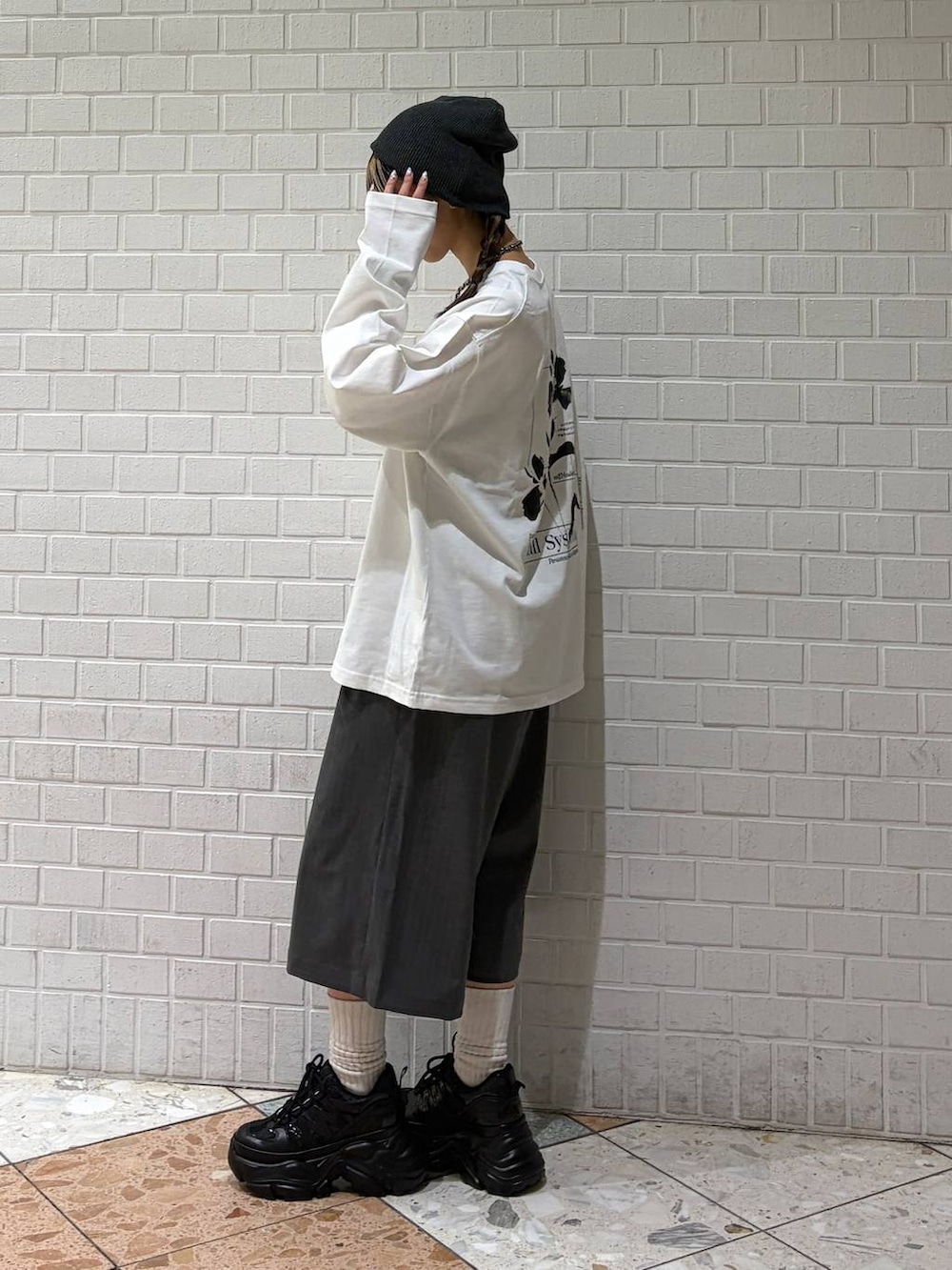 ブラック系のスニーカー、ホワイト系のTシャツ/カットソー、グレー系のスラックスを着用したレディースの春コーディネートの3枚目の写真