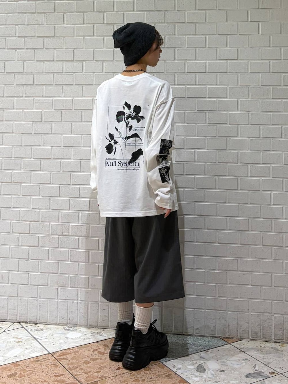 ブラック系のスニーカー、ホワイト系のTシャツ/カットソー、グレー系のスラックスを着用したレディースの春コーディネートの6枚目の写真