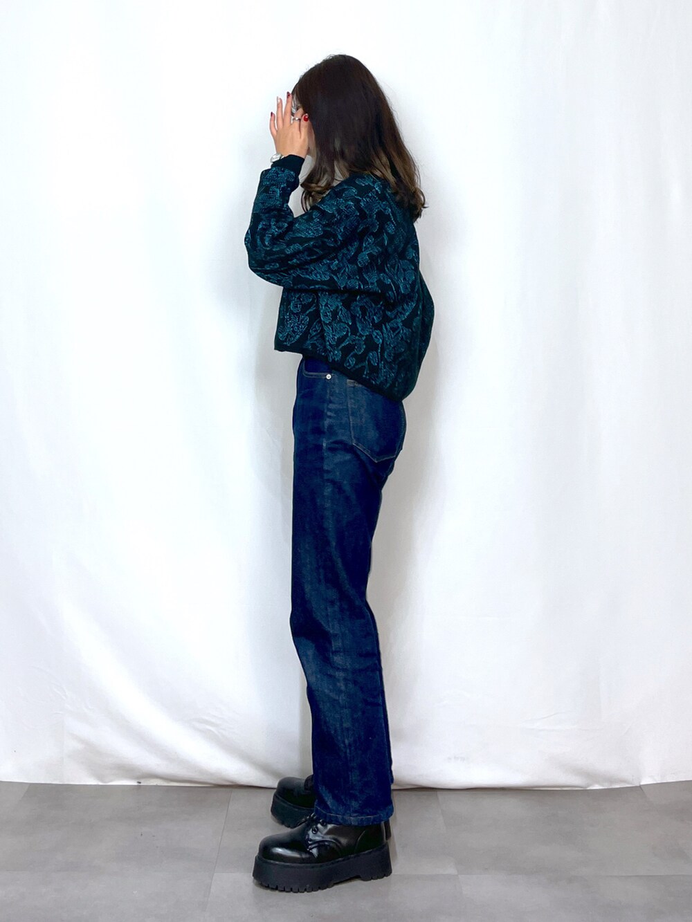 ブラック系のニット/セーター、ブルー系のデニムパンツ、ブラック系のベルトを着用したレディースの冬コーディネートの2枚目の写真