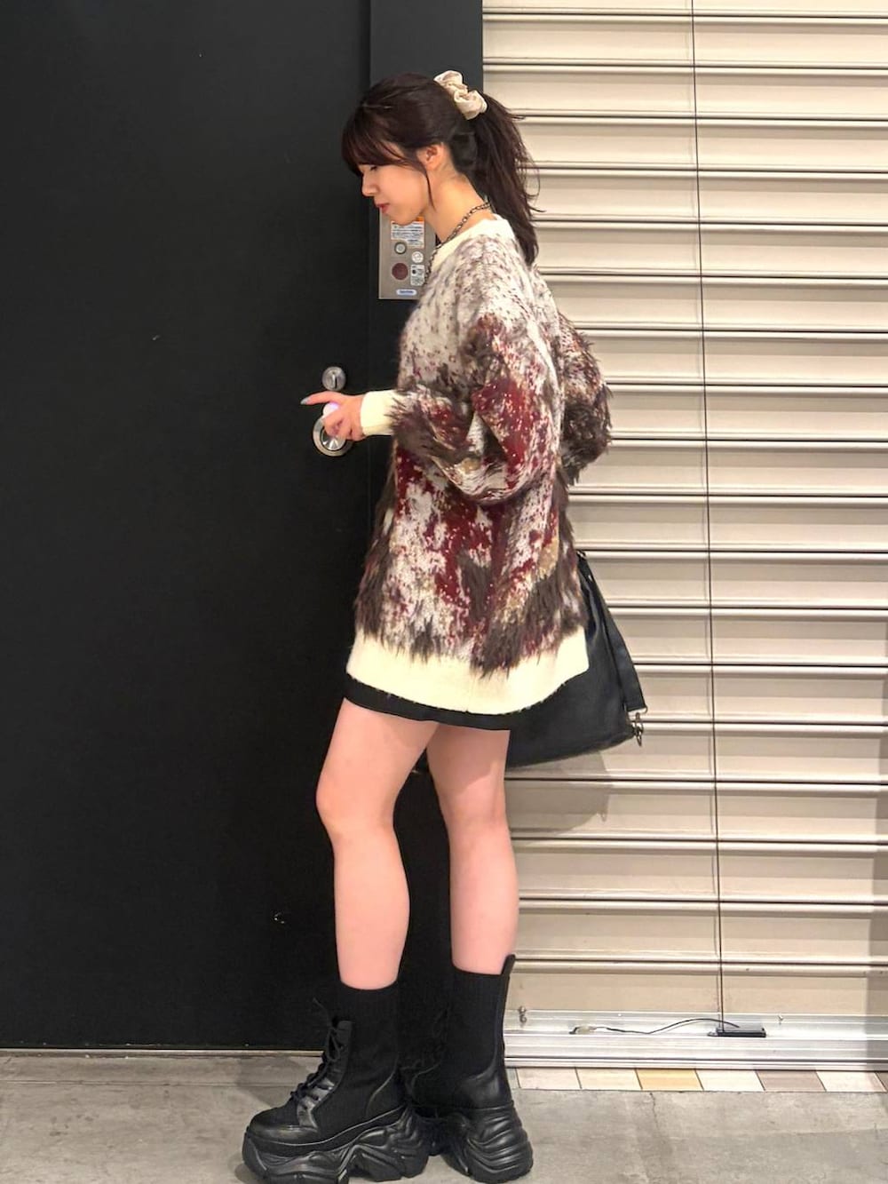 ホワイト系のニット/セーター、ブラック系のブーツ、ブラック系のショルダーバッグを着用したレディースの夏コーディネートの4枚目の写真