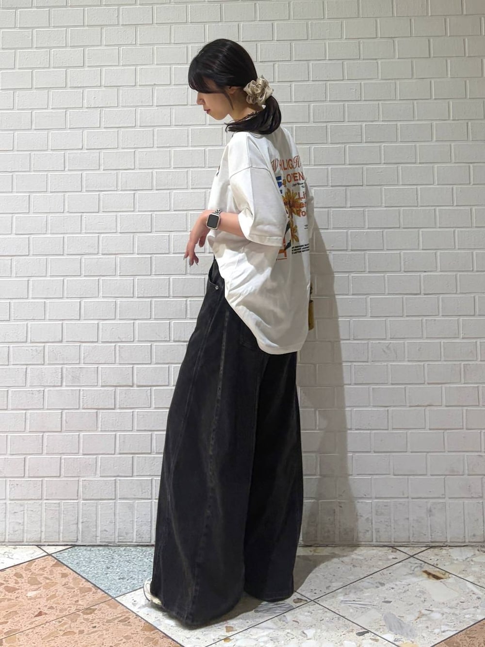 ブラック系のデニムパンツ、イエロー系のショルダーバッグ、ホワイト系のTシャツ/カットソーを着用したレディースの夏コーディネートの3枚目の写真