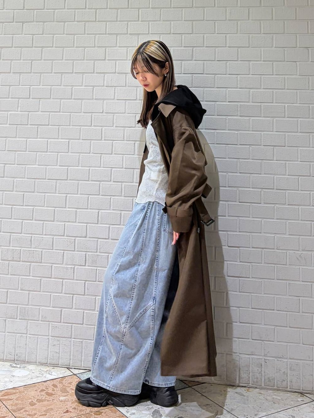 ブラック系のブーツ、ブラウン系のトレンチコート、ブルー系のデニムパンツを着用したレディースの春コーディネートの7枚目の写真