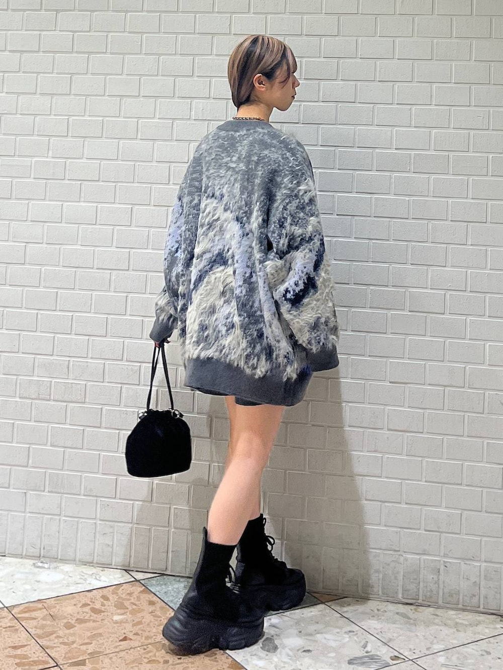 ブラック系のブーツ、ホワイト系のカーディガン/ボレロ、ホワイト系のニット/セーターを着用したレディースの冬コーディネートの5枚目の写真