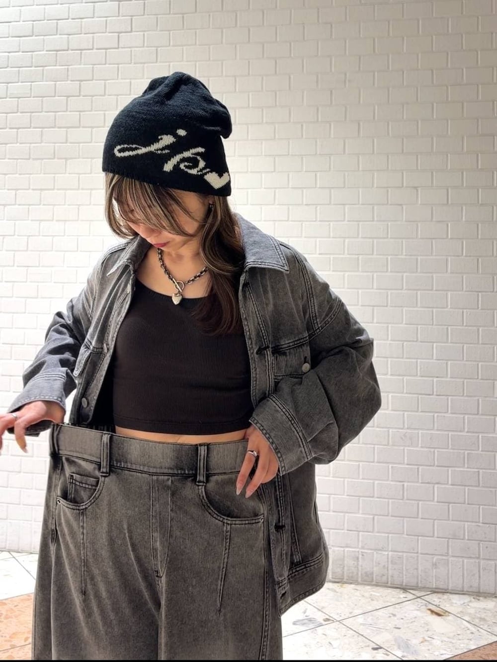 ホワイト系のスニーカー、ブラック系のブルゾン、ブラック系のデニムパンツを着用したレディースの春コーディネートの3枚目の写真