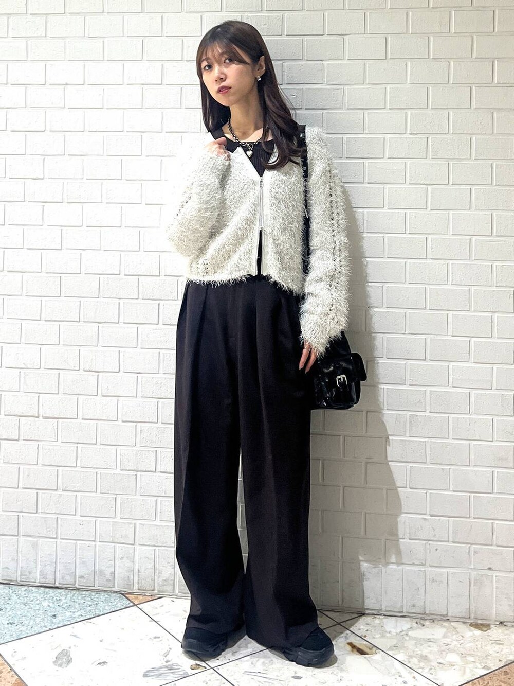 ブラック系のスニーカー、ブラック系のブルゾン、ホワイト系のカーディガン/ボレロを着用したレディースの秋コーディネートの4枚目の写真