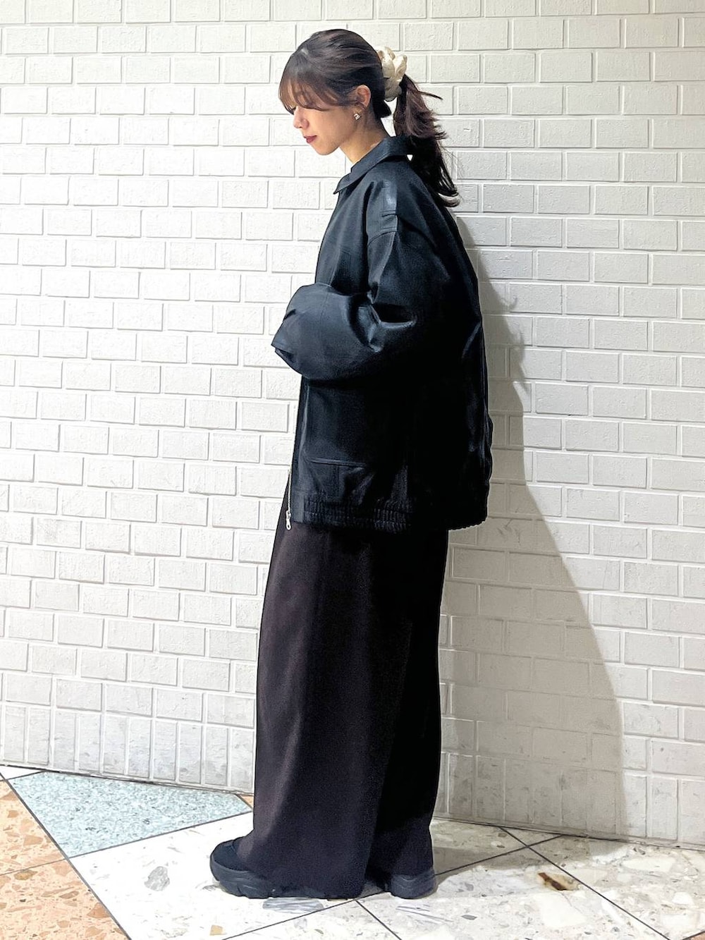 ブラック系のスニーカー、ブラック系のブルゾン、ホワイト系のカーディガン/ボレロを着用したレディースの秋コーディネートの2枚目の写真