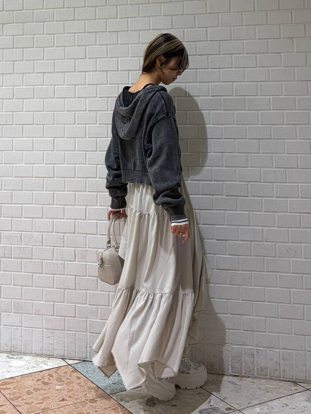 ホワイト系のスニーカー、ベージュ系のスカート、ホワイト系のボストンバッグを着用したレディースの冬コーディネートの4枚目の写真