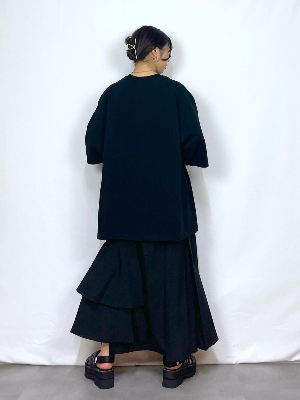 ブラック系のTシャツ/カットソー、ブラック系のスカート、ブラック系のサンダルを着用したレディースの春コーディネートの5枚目の写真