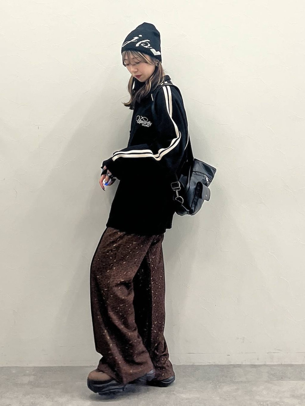 ブラウン系のブーツ、ブラック系のショルダーバッグ、ブラック系のジャージを着用したレディースの冬コーディネートの6枚目の写真