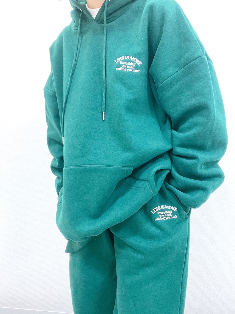 グリーン系のパーカー、グリーン系のスウェットパンツ、ブラック系のブーツを着用したレディースの冬コーディネートの3枚目の写真