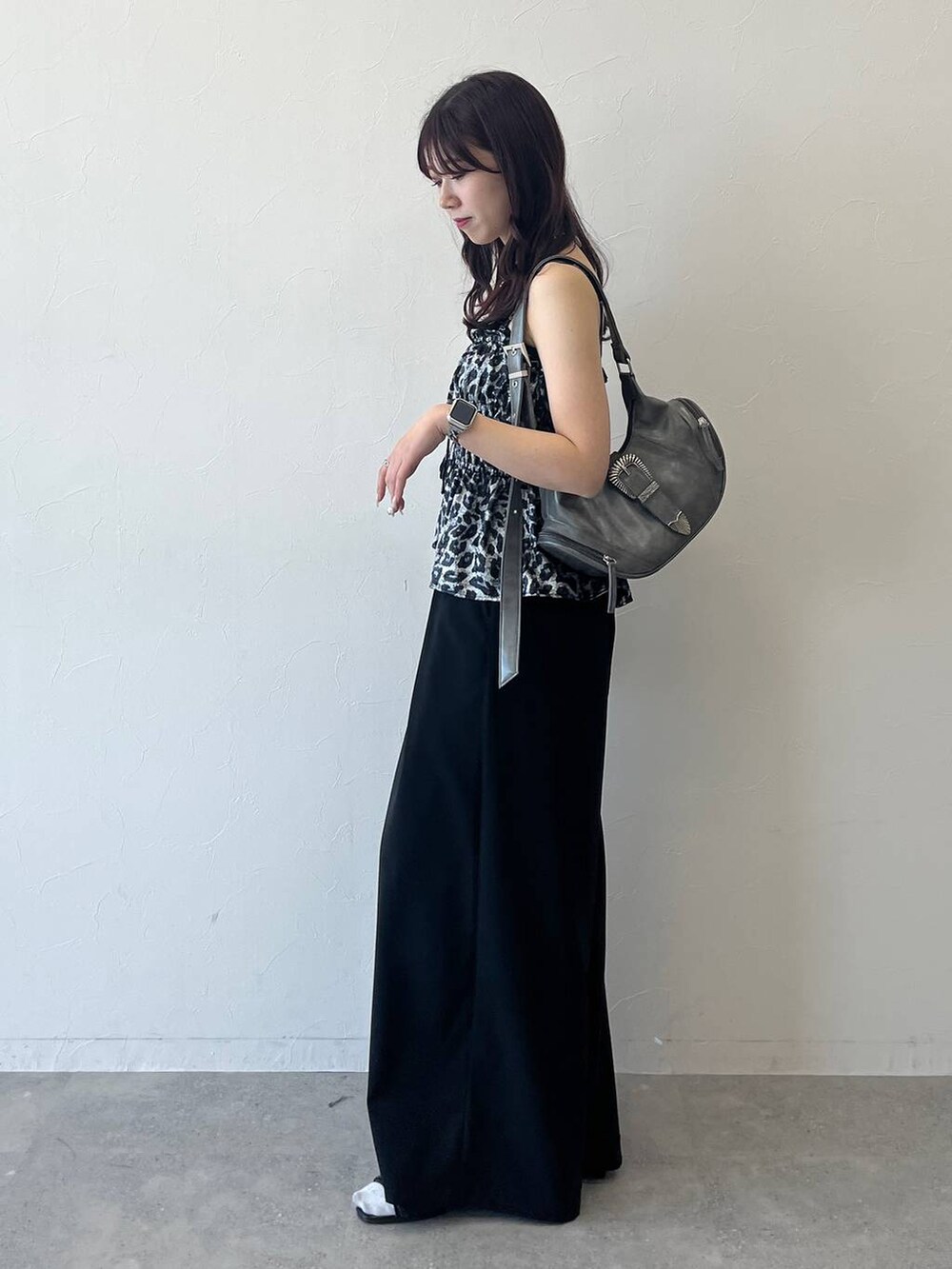 グレー系のショルダーバッグ、ブラック系のスラックスを着用したレディースの夏コーディネートの2枚目の写真