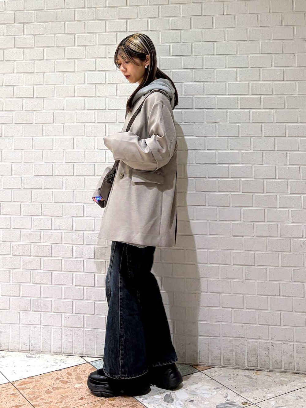 ブラック系のブーツ、ブルー系のデニムパンツ、グレー系のパーカーを着用したレディースの春コーディネートの6枚目の写真