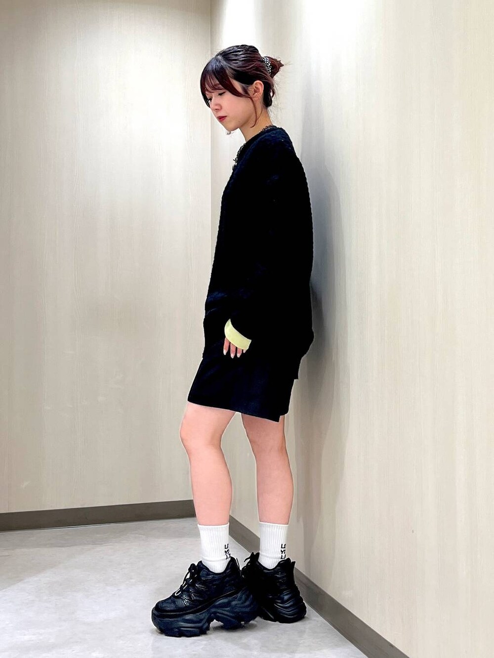 ブラック系のスニーカー、ブラック系のニット/セーター、イエロー系のTシャツ/カットソーを着用したレディースの冬コーディネートの2枚目の写真