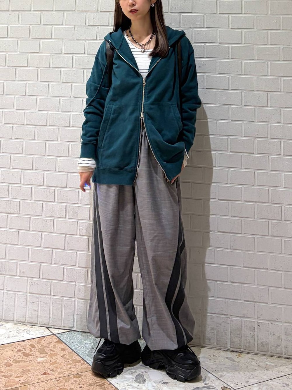 ブラック系のブーツ、グリーン系のパーカー、ブラウン系のショルダーバッグを着用したレディースの冬コーディネートの4枚目の写真