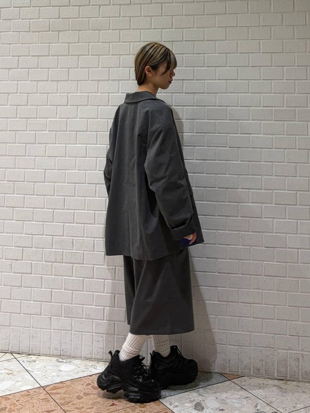 ブラック系のスニーカー、ホワイト系のTシャツ/カットソー、グレー系のスラックスを着用したレディースの春コーディネートの9枚目の写真