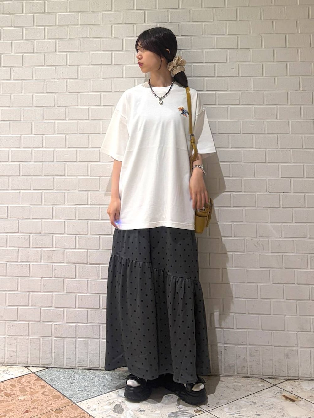 イエロー系のショルダーバッグ、ブラック系のサンダル、ホワイト系のTシャツ/カットソーを着用したレディースの夏コーディネートの4枚目の写真