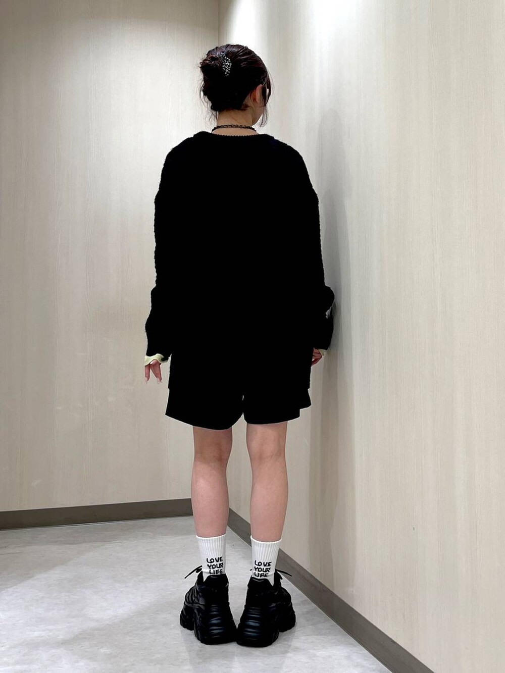 ブラック系のスニーカー、ブラック系のニット/セーター、イエロー系のTシャツ/カットソーを着用したレディースの冬コーディネートの3枚目の写真