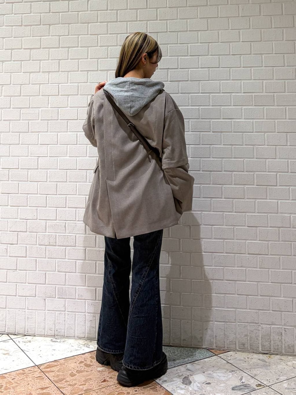 ブラック系のブーツ、ブルー系のデニムパンツ、グレー系のパーカーを着用したレディースの春コーディネートの2枚目の写真