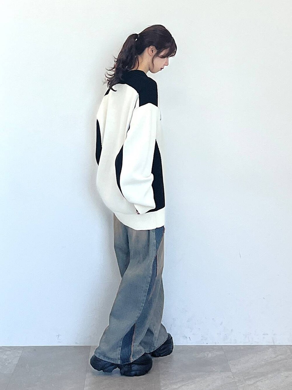 ブルー系のデニムパンツ、ブラック系のブーツ、ブラック系のニット/セーターを着用したレディースの秋コーディネートの2枚目の写真