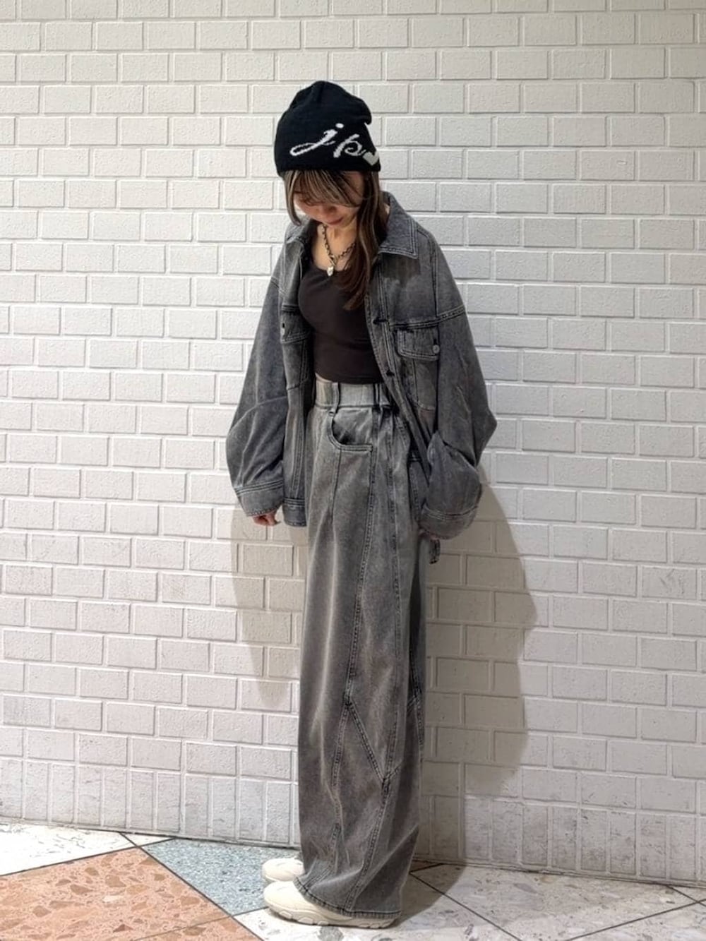 ホワイト系のスニーカー、ブラック系のブルゾン、ブラック系のデニムパンツを着用したレディースの春コーディネートの2枚目の写真