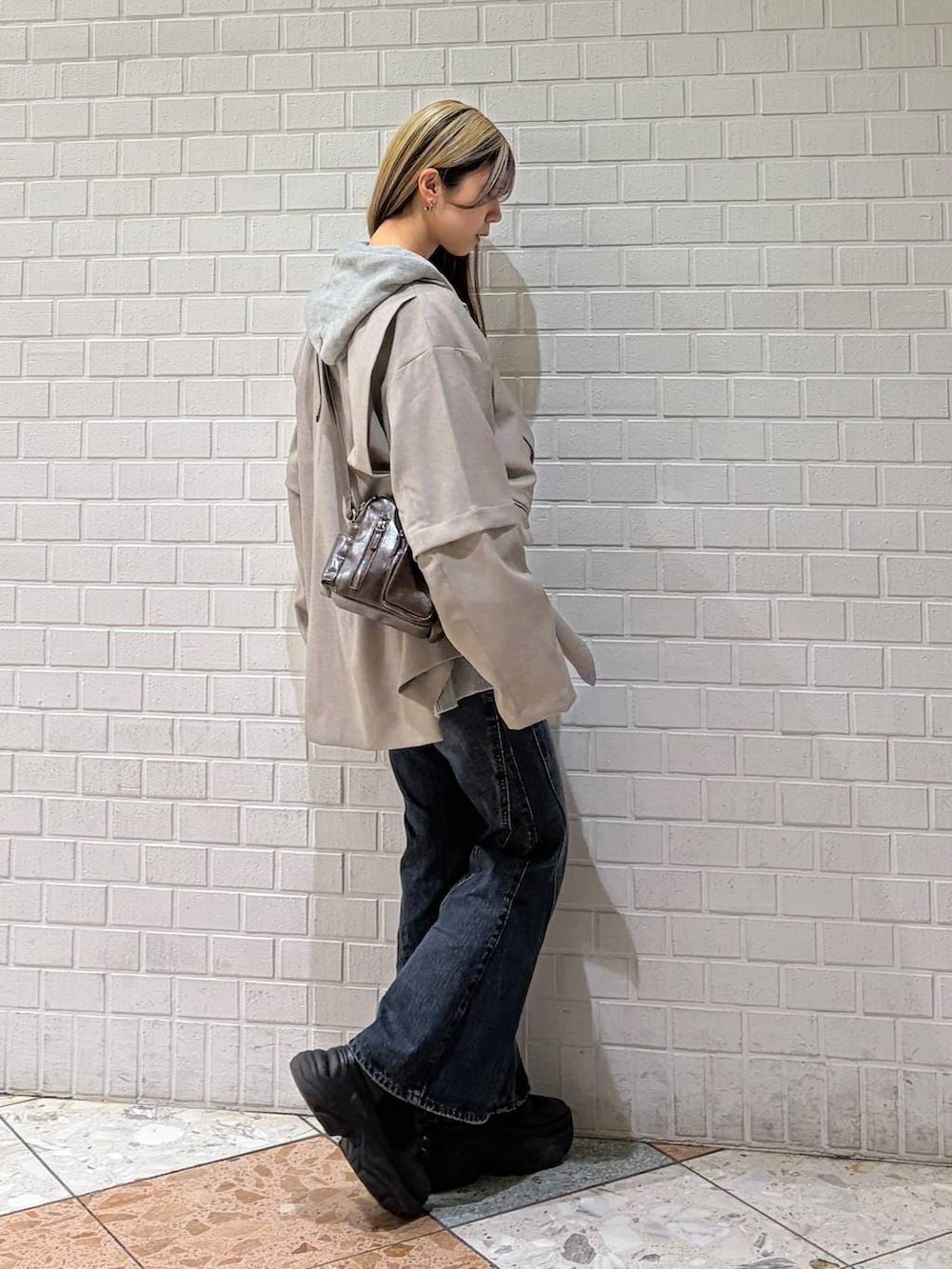 ブラック系のブーツ、ブルー系のデニムパンツ、グレー系のパーカーを着用したレディースの春コーディネートの4枚目の写真