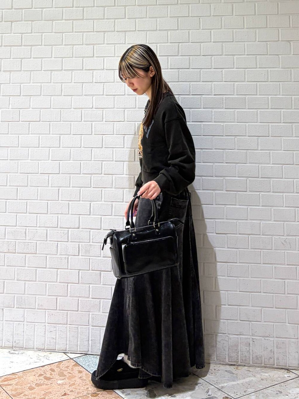 グレー系のスウェット、ブラック系のショルダーバッグ、ブラック系のデニムスカートを着用したレディースの春コーディネートの5枚目の写真