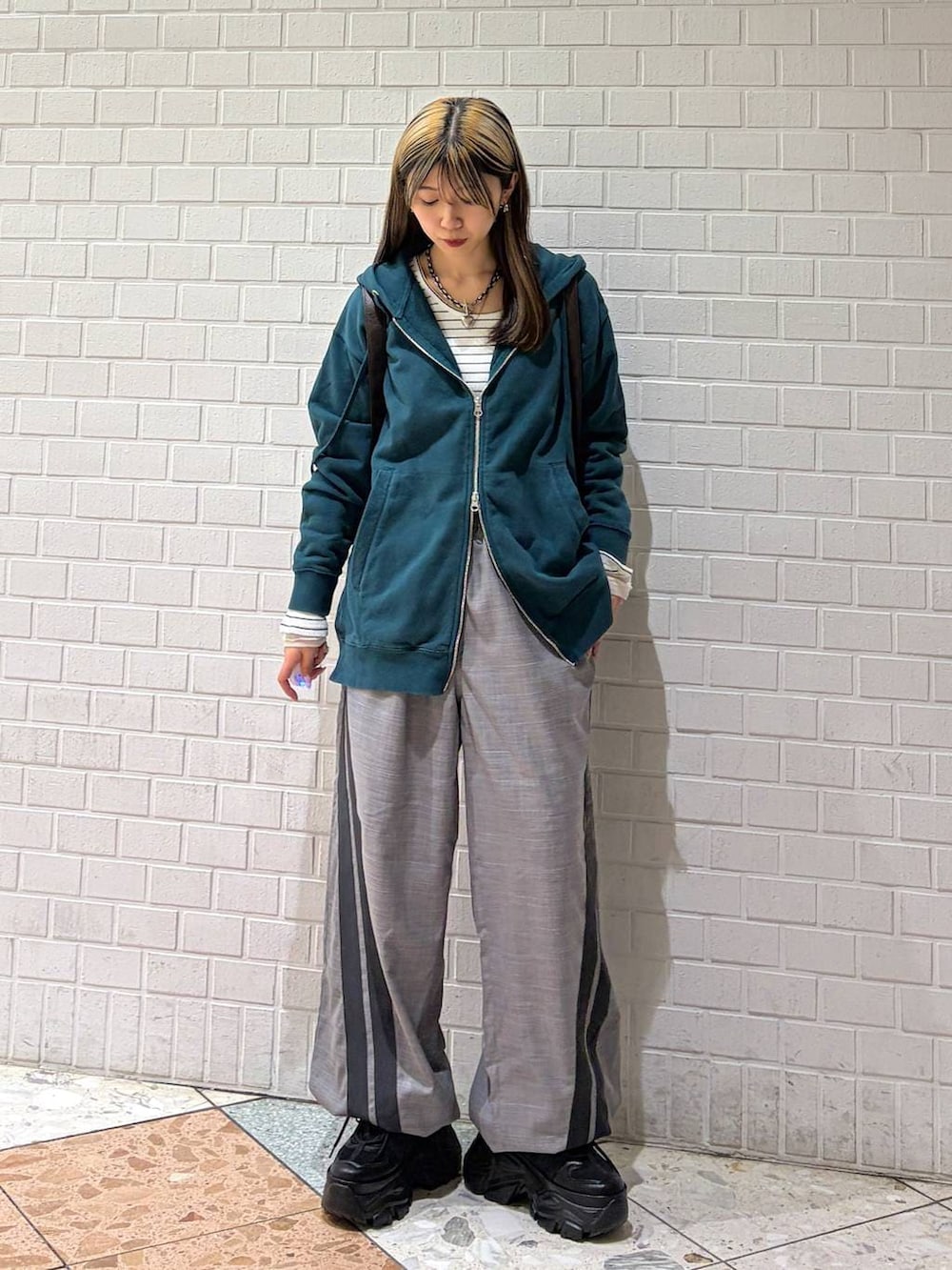 ブラック系のブーツ、グリーン系のパーカー、ブラウン系のショルダーバッグを着用したレディースの冬コーディネートの7枚目の写真