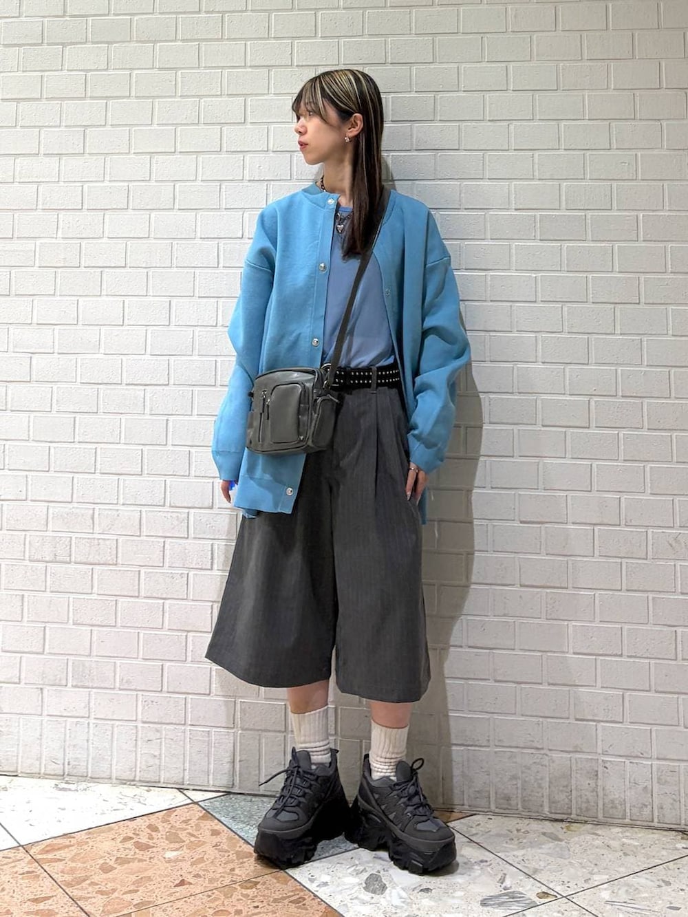 グレー系のスニーカー、グレー系のショルダーバッグ、グレー系のスラックスを着用したレディースの春コーディネートの4枚目の写真