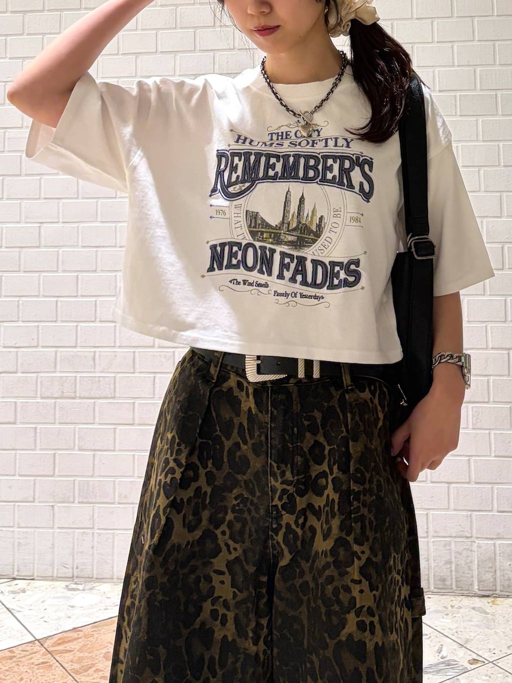 ブラック系のスニーカー、ブラック系のショルダーバッグ、ホワイト系のTシャツ/カットソーを着用したレディースの夏コーディネートの3枚目の写真