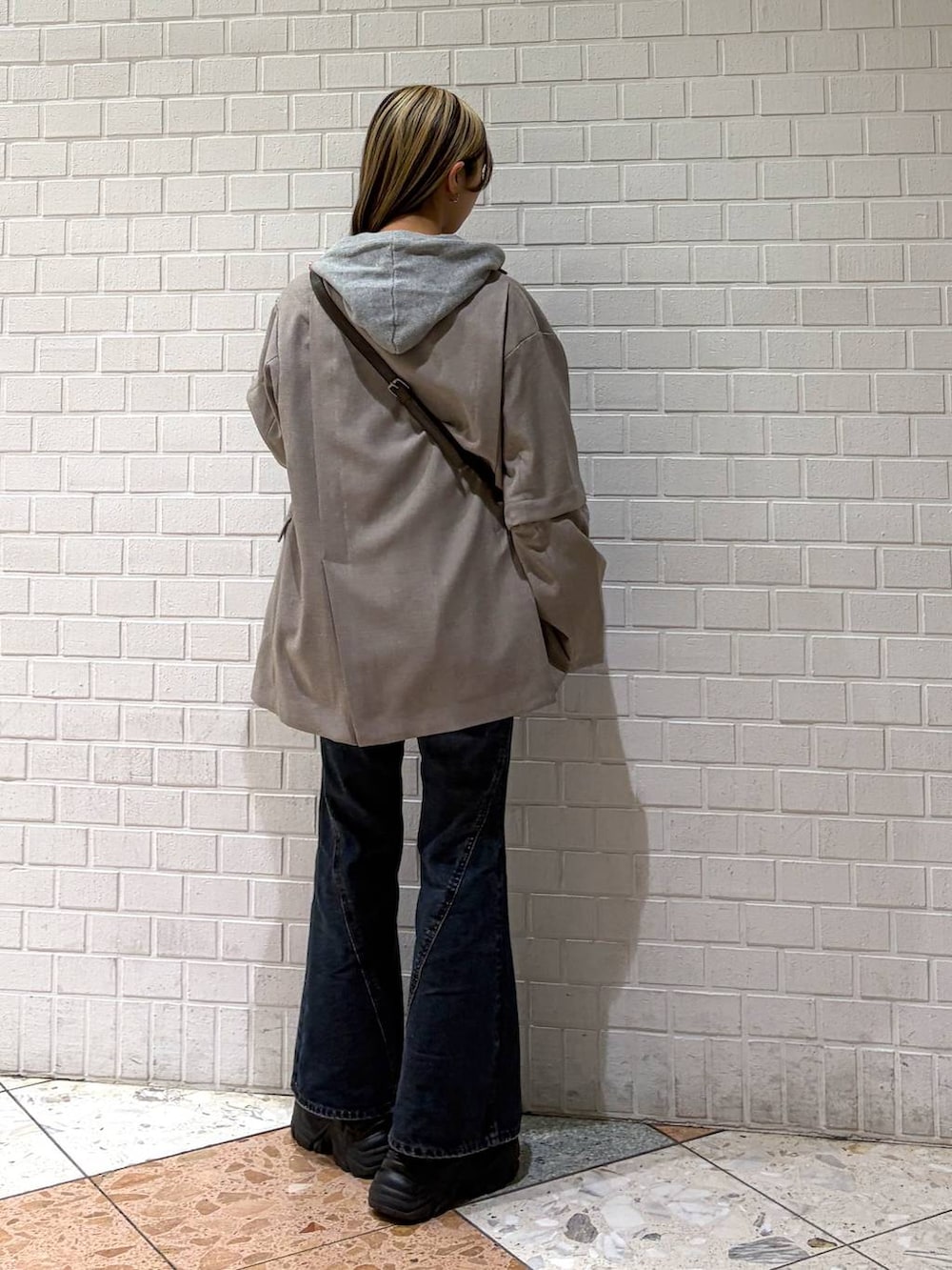 ブラック系のブーツ、ブルー系のデニムパンツ、グレー系のパーカーを着用したレディースの春コーディネートの5枚目の写真