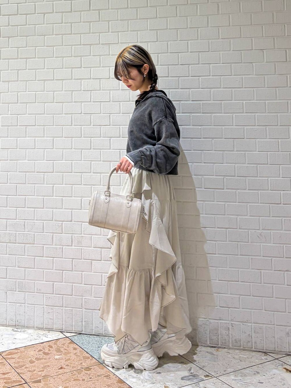 ホワイト系のスニーカー、ベージュ系のスカート、ホワイト系のボストンバッグを着用したレディースの冬コーディネートの2枚目の写真