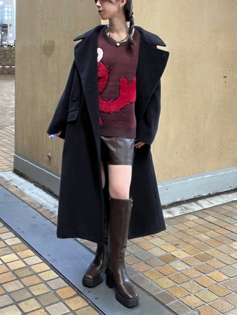 ブラック系のチェスターコート、ブラウン系のブーツ、ブラウン系のその他パンツを着用したレディースの冬コーディネートの3枚目の写真