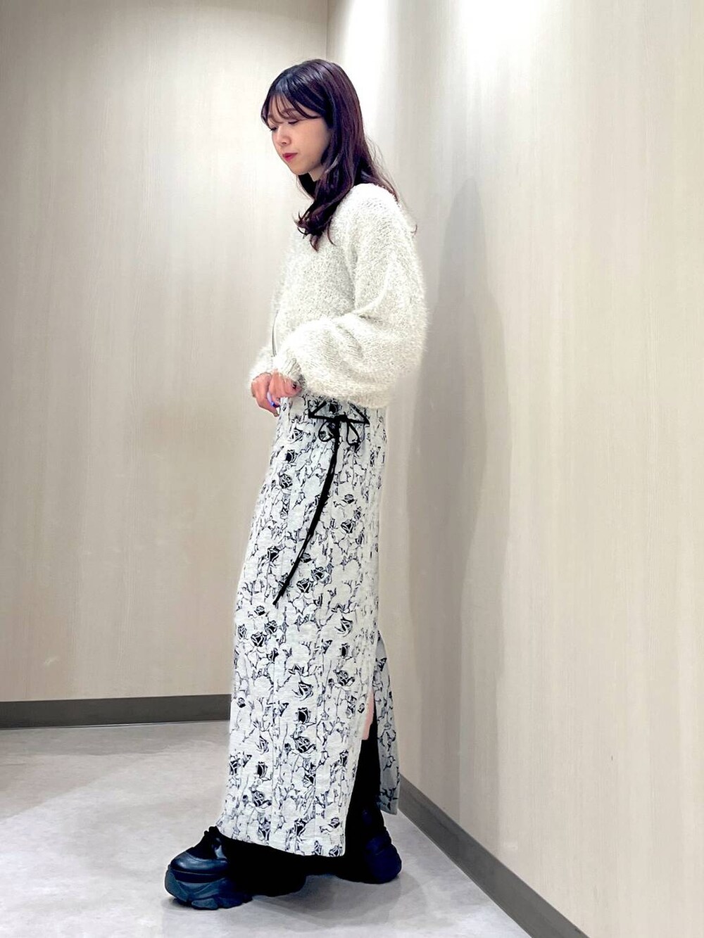 ブラック系のブーツ、ホワイト系のカーディガン/ボレロ、ブラック系のニット/セーターを着用したレディースの秋コーディネートの2枚目の写真