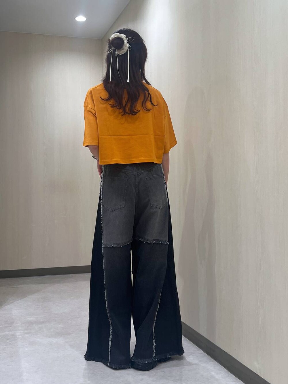 ブラック系のスニーカー、オレンジ系のTシャツ/カットソー、ブラック系のデニムパンツを着用したレディースの夏コーディネートの3枚目の写真