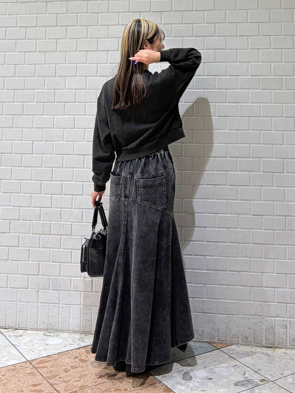 グレー系のスウェット、ブラック系のショルダーバッグ、ブラック系のデニムスカートを着用したレディースの春コーディネートの3枚目の写真
