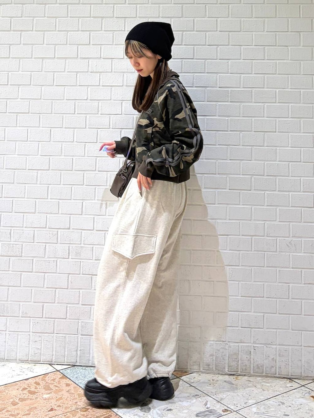 ブラック系のブーツ、ブラウン系のショルダーバッグ、グリーン系のジャージを着用したレディースの春コーディネートの2枚目の写真