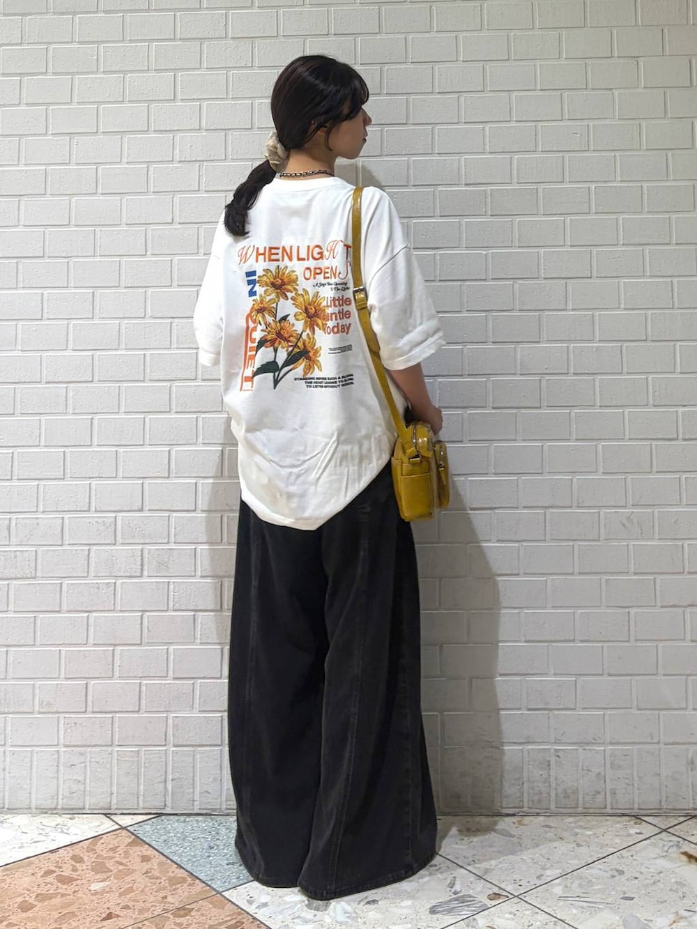 ブラック系のデニムパンツ、イエロー系のショルダーバッグ、ホワイト系のTシャツ/カットソーを着用したレディースの夏コーディネートの2枚目の写真