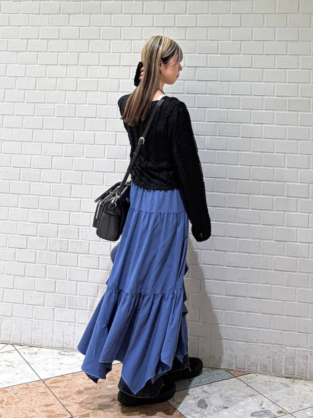 ブルー系のデニムパンツ、ブルー系のスカート、ブラック系のショルダーバッグを着用したレディースの春コーディネートの3枚目の写真