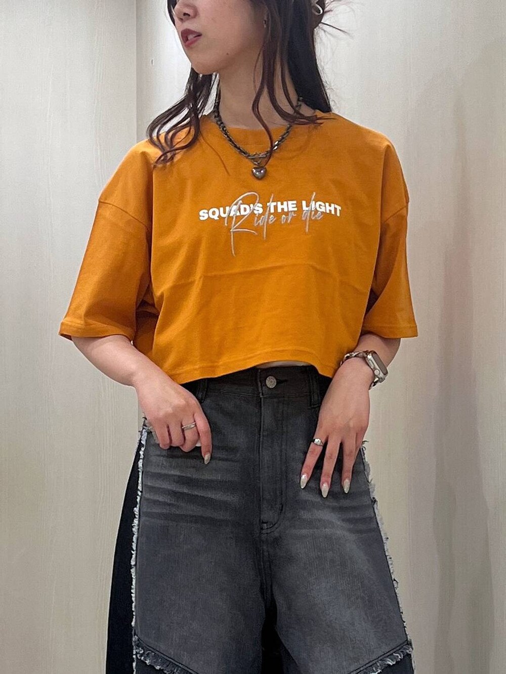ブラック系のスニーカー、オレンジ系のTシャツ/カットソー、ブラック系のデニムパンツを着用したレディースの夏コーディネートの4枚目の写真