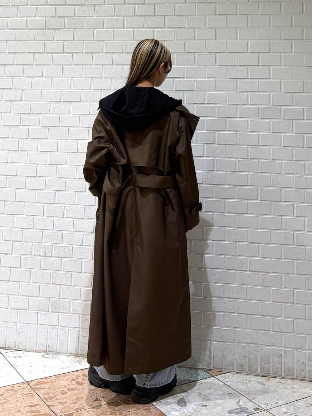 ブラック系のブーツ、ブラウン系のトレンチコート、ブルー系のデニムパンツを着用したレディースの春コーディネートの3枚目の写真