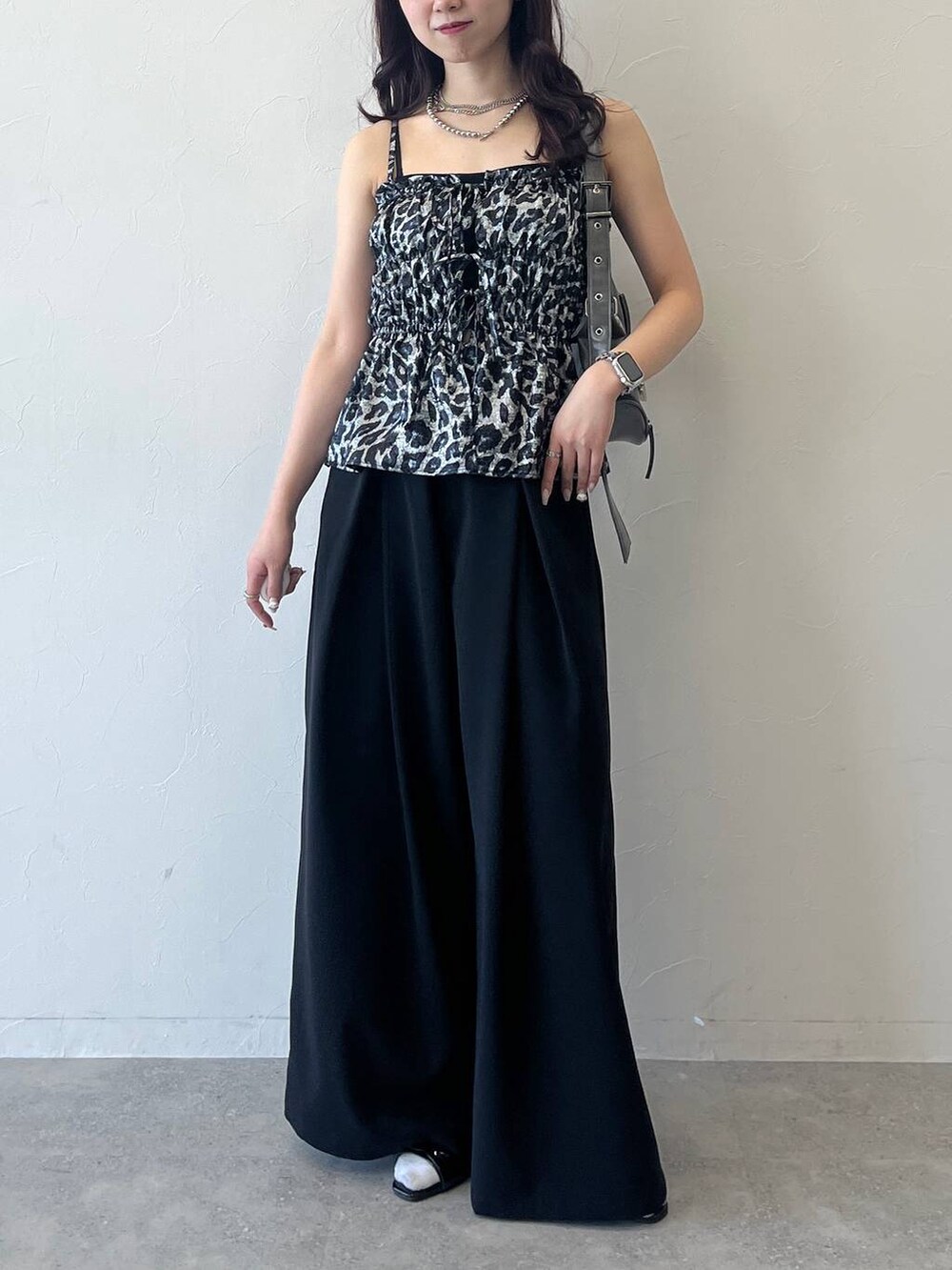 グレー系のショルダーバッグ、ブラック系のスラックスを着用したレディースの夏コーディネートの4枚目の写真